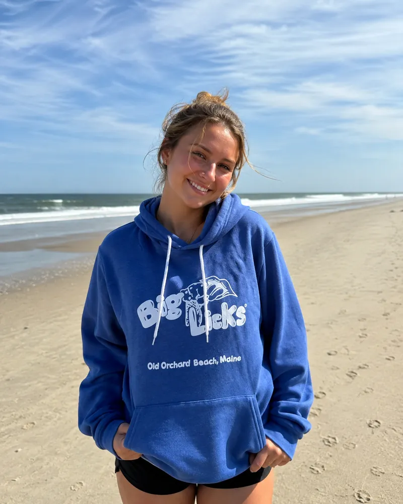 A woman wearing the royal blue Big Licks hooded sweatshirt on the beach