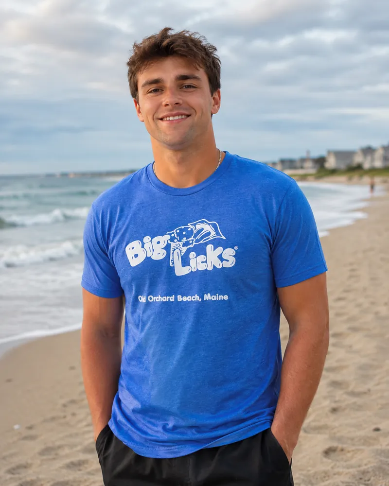 A man wearing the royal blue Big Licks t-shirt on the beach at Old Orchard Beach
